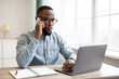 © Prostock-studio - Serious Black Businessman Talking On Mobile Phone Sitting At Workplace