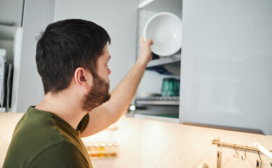 Young man washing dishes in the kitchen.