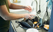 © snedorez - Young man washing dishes in the kitchen.