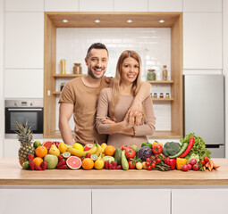 Sticker - Couple posing in a kitchen behind a counter with a pile of fresh fruits and vegetables