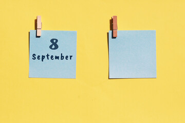 8 September. 8th day of the month, calendar date. Two blue sheets for writing on a yellow background. Top view, copy space. Autumn month, day of the year concept