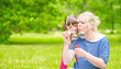 © Ermolaev Alexandr - Little girl with syndrome down and her mother blow bubbles in a summer park. Empty space for text