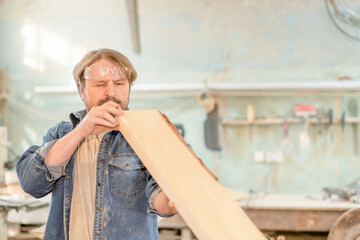 Wall Mural - Man looking and choosing wood or testing wood plank in the workshop. Empty space for text