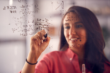 Brainstorming Businesswoman Or Mathematician Drawing Graph Calculation On Glass Screen In Office