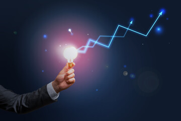 Poster - Business idea concept with businessman hand carrying glowing light bulb and digital blue arrows up at abstract background