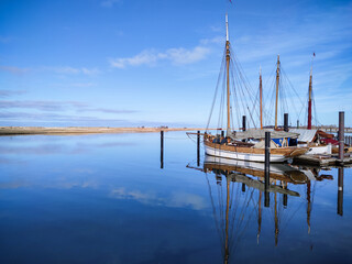 Photo of modern and old boats in harbor near wooden pier in calm sunset light