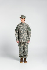 Wall Mural - Woman in military clothes standing on grey background