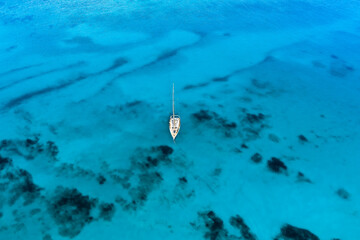 Canvas Print - View from above, stunning aerial view of a sail boat sailing on a turquoise and transparent water. Sardinia, Italy.