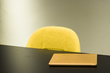 Wall Mural - Selective focus shot of a laptop on the black table and yellow chair in the office