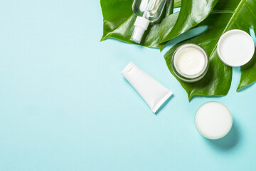 Wall Mural - natural cosmetic products at blue background with green leaves. cream, mask, lotion for face and bod