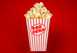 Full popcorn in a classic popcorn box on a red background.