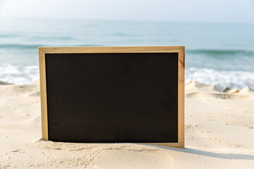 Chalkboard with a wooden frame Blank Chalk board for write text, message or advertising, placed on the sand of a beach. Empty blackboard on sandy beach.