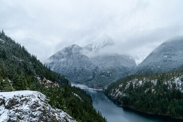 Wall Mural - A mountain lake in winter surrounded by snow covered pine trees.