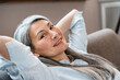 © InsideCreativeHouse - Cheerful middle-aged woman with grey hair relaxing on the couch