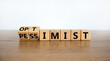 Pessimist or optimist symbol. Turned cubes and changed the word 'pessimist' to 'optimist'. Beautiful wooden table, white background. Business and optimist or pessimist concept. Copy space.