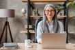© InsideCreativeHouse - Confident middle-aged grey-haired woman working on the laptop in modern office