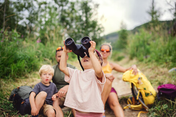 Wall Mural - family with small children hiking outdoors in summer nature, sitting and resting.