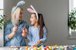 © Angelov - Attractive young woman with little cute girl are preparing for Easter celebration. Mom and daughter wearing bunny ears are spending time together before Easter while painting eggs.