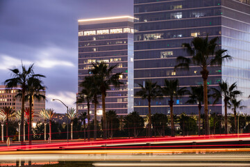 Twilight evening view of traffic streaming by the downtown skyline of Irvine, California, USA.