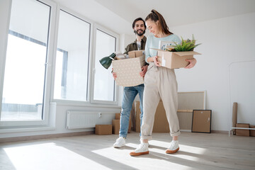 Young couple with boxes moving in new flat, new home and relocation concept.