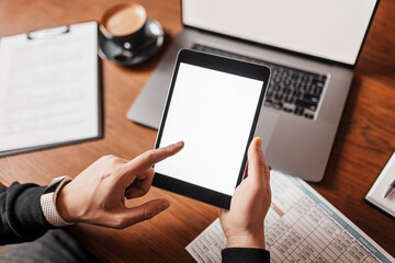 Male hands holding tablet with blank background at workplace. Businessman working at desk with documents