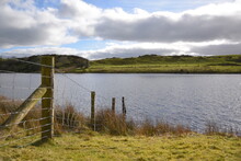 A Barbed Wire Fence Extended Out Into A Lake In Wales