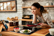 © Drazen - Young woman feeling dissatisfied while cooking and looking at recipe on the Internet.