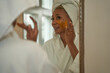 © Mhandy/Creative Flame - Black woman puts on DIY facial mask, skincare self care