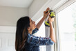 © Gerald Carter/Creative Flame - Indian woman using drill power tool to install blinds, DIY home improvement project