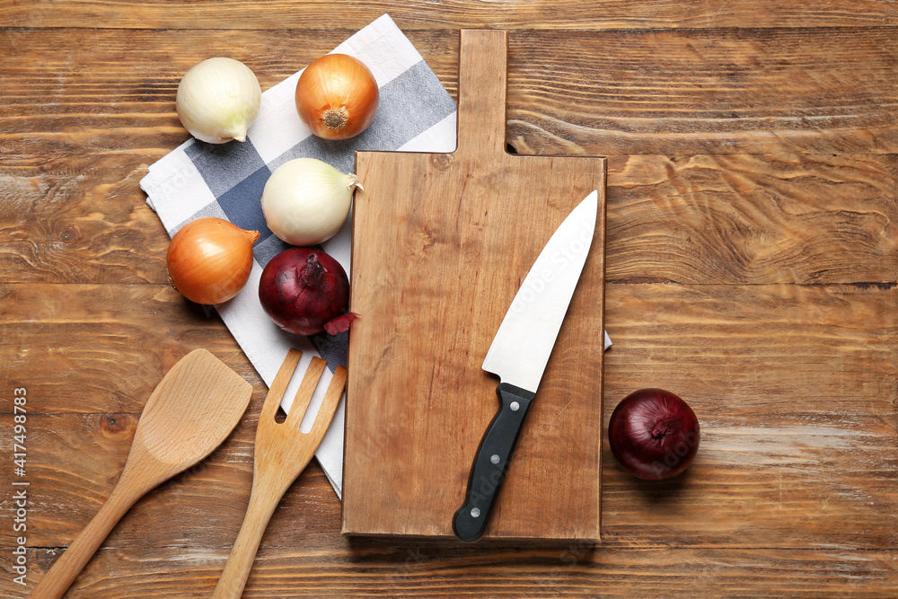 Cutting board, knife and onion on wooden background