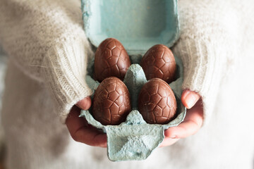 Wall Mural - Woman hands holding egg carton with chocolate eggs. Easter celebration concept