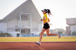 © EduLife Photos - A young Asian woman athlete runner jogging on running track in city stadium in the sunny morning to keep fitness and healthy lifestyle. Young fitness woman runs on stadium track. Sport and recreation