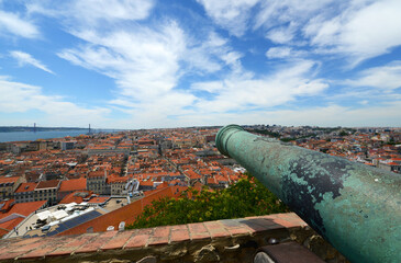 Cannon on top of Castle of Sao Jorge (Portuguese: Castelo de Sao Jorge) with the Baixa district skyline and Tagus River at the background in Lisbon, Portugal.