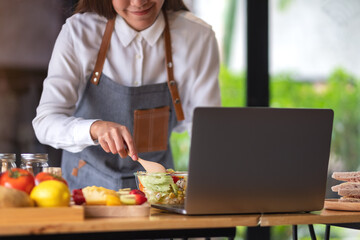 A woman videoblogger cooking in the kitchen and filming, online learning cooking class concept