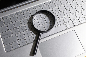 Magnifying glass on laptop computer keyboard. concept of search and web technology