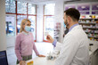 © littlewolf1989 - Pharmacist selling vitamins and medicines to the customer in pharmacy shop during corona virus pandemic.