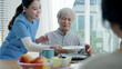 © ChayTee - Attractive young senior asian citizen couple happy sit, talk, eat soup for healthy nutrition breakfast meal on dining table at home in morning in routine lifestyle in old asia nursing in-home care.