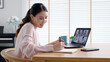 © ChayTee - Back view of business woman talking about sale report in video conference. Asian team using laptop and tablet online meeting in video call.Working from home, Working remotely and Social isolation.