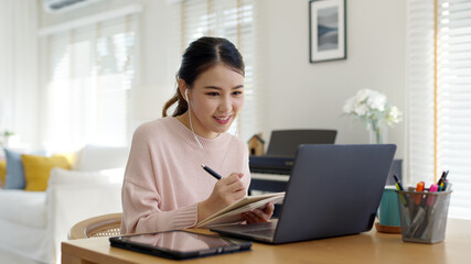 candid young attractive asian female employee wear earphone listen to digital online course developm