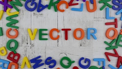 Fototapete - Brightly colored alphabet letters framing the word on a grey wood background viewed as a flat lay still life. Stop motion, top view