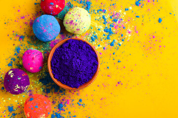 Blue holi powder in bowl and multicolors ball isolated on yellow background