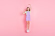 Full length body size photo of amazed small girl jumping high showing little big size isolated pastel pink color background