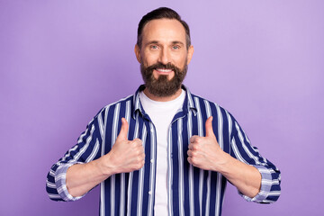 Photo of cheerful guy raise two thumbs up beaming smile wear striped shirt isolated purple color background