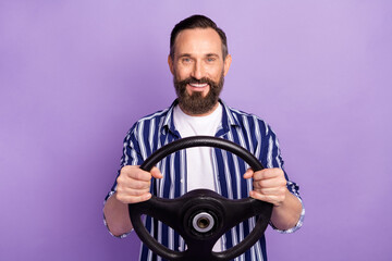 Poster - Photo of mature man driver hold steering wheel isolated over purple color background