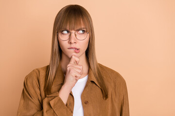 Sticker - Photo of minded thoughtful young woman look empty space hold hand chin bite lip isolated on beige color background