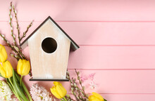 Flat Lay Composition With Bird House And Flowers On Pink Wooden Background. Space For Text