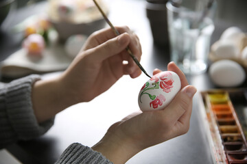 Wall Mural - Woman painting Easter egg at black table, closeup