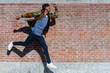 © MandriaPix - afro american stylish man jumping in the air, shadows on the brick wall backgroung, positive and active image, dinamic pose and copy space