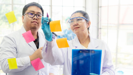 Wall Mural - team work asian woman and man scientists analyzing study data and evaluating microscope success for 