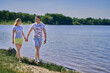 © Aleksandr - A young couple in love holds hands and walks along the lake.